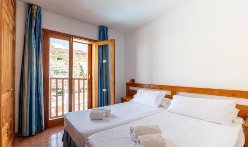 a bedroom with two beds and a large window at Apartamentos Montecarlo in Puerto Rico de Gran Canaria