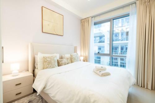 ein Schlafzimmer mit einem weißen Bett mit einem Fenster in der Unterkunft Island Bliss 2 BR with Private Beach and Pool in Al Marjan Island in Ras al Khaimah