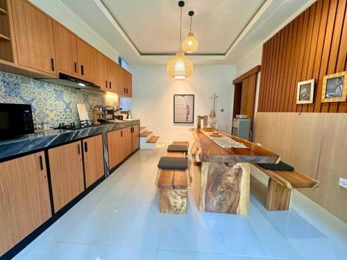 a large kitchen with wooden cabinets and a wooden table at Villa Lulu - Uluwatu Nusa Dua in Ungasan