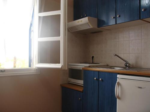 a kitchen with blue cabinets and a sink at Panorama Apartments in Marathokampos