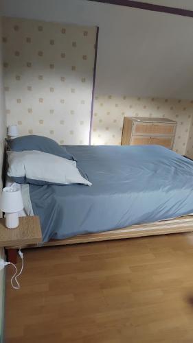 a bed with blue sheets and pillows in a room at gîte 8 personnes Les Marqueries in La Flèche