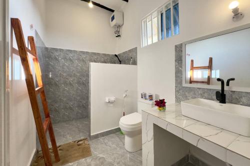 a bathroom with a sink and a toilet and a mirror at Zanzibar Lodge in Kiwengwa
