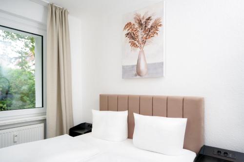 a bedroom with a bed with white sheets and a window at SHIN APARTMENTS in Essen