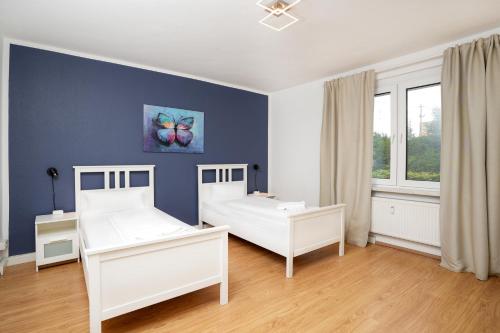 a bedroom with two beds and a blue wall at Shin West in Essen