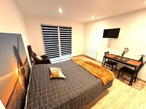 une chambre avec un lit, un bureau et une télévision dans l'établissement Refuge des voyageurs - studio neuf - Ancrage indépendant Rez de jardin, à Plouédern