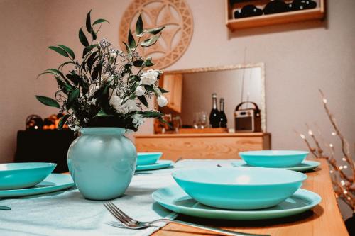 een tafel met borden en een blauwe vaas met bloemen bij Widokowy Zakątek u Kamila in Zakopane