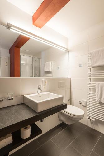 a white bathroom with a sink and a toilet at Hotel Alpina Luzern in Lucerne