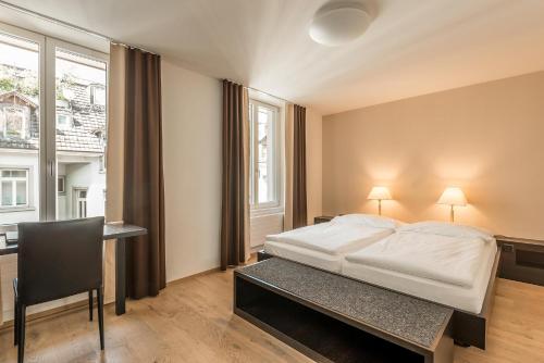 a bedroom with a bed and a desk and a window at Hotel Alpina Luzern in Lucerne