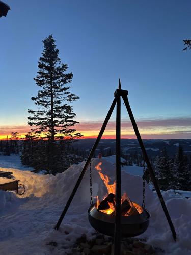 a fire pit in the snow at sunset at New chalet with great view in Hafjell
