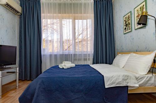 ein Schlafzimmer mit einem Bett mit einer blauen Decke und einem Fenster in der Unterkunft 501 Чистая и уютная квартира в хорошем районе in Qapschaghai