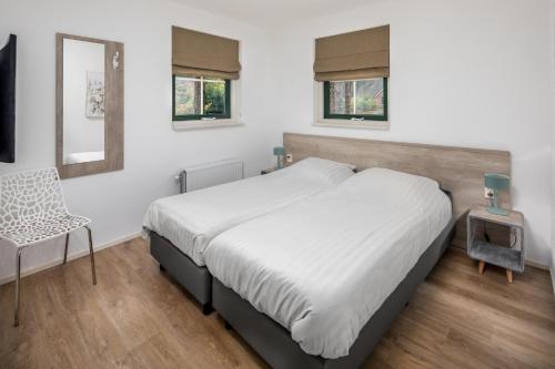 une chambre avec un lit, une chaise et un miroir dans l'établissement Landgoed Het Grote Zand, à Hooghalen