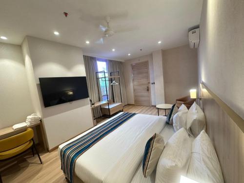 a hotel room with a large bed and a television at Bluestone Prime by The Cosy Hotels in New Delhi