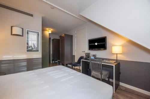 a bedroom with a bed and a desk and a tv at Fletcher Hotel - Restaurant Nautisch Kwartier in Huizen