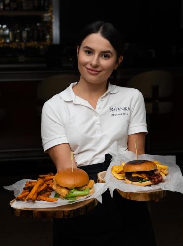 a woman holding two hamburgers and french fries at Eurohotel Swarzędz in Swarzędz