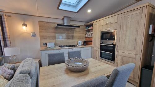 a kitchen with a wooden table with chairs and a dining room at The Good Life, The Boulevard, Selsey in Selsey