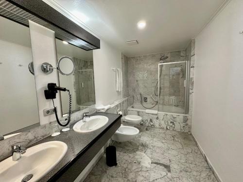 a bathroom with two sinks and a toilet and a shower at Hotel Residenz in Bad Neustadt an der Saale