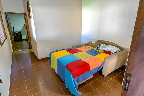 ein Bett in einem Zimmer mit einer bunten Decke in der Unterkunft Conforto e praia a poucos passos in Guriri