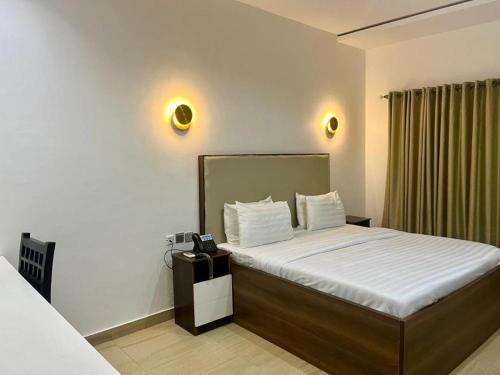 a bedroom with a bed with a phone on it at Greywood Hotel and Apartments in Ikeja