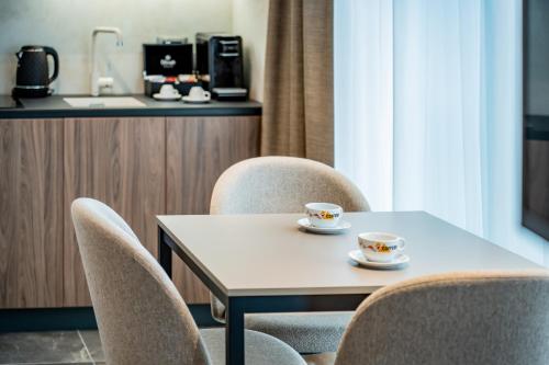 a table with chairs and two cups on it at Novita Hotel in Sofia