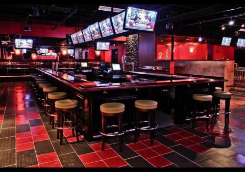 a bar with stools in a room with televisions at Ramada by Wyndham Rochelle Park Near Paramus in Rochelle Park