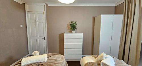 a bedroom with a bed and a dresser with a plant at The Kilnwood House - 3 Bed w Free Parking and Fast WiFi - Contractor Ready in Crawley