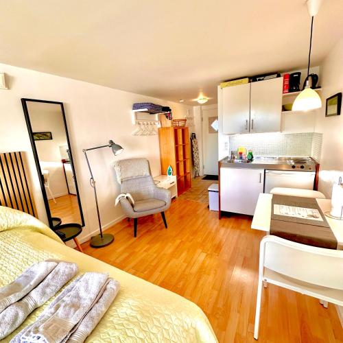 a bedroom with a bed and a desk and a kitchen at Cosy apartment with private terrace in Vallensbæk