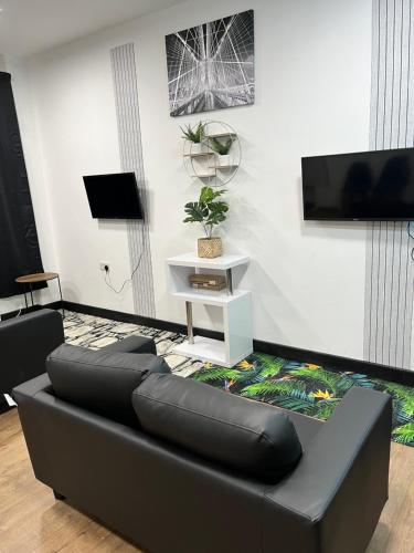 a living room with a black couch and a tv at KD Homes in Horwich