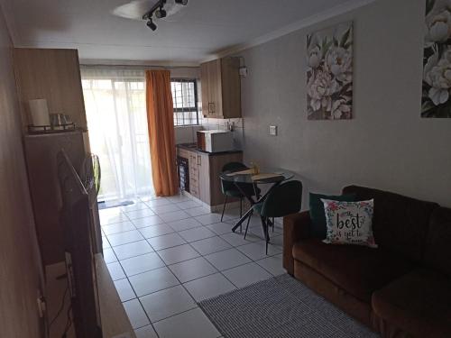 a living room with a couch and a kitchen at Sandalion Cottage near OR Tambo Airport & Greenstone in Edenvale
