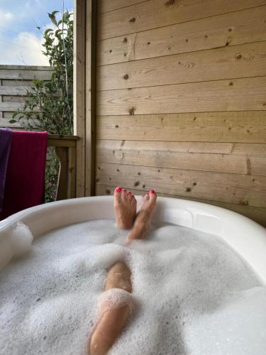 a person in a bath tub with their feet in it at WildView Cosy Glamping with Outdoor Bath and stunning scenery in Helston