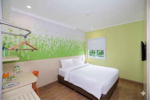 a bedroom with a white bed and a desk and a window at Palette Legian Beach in Legian