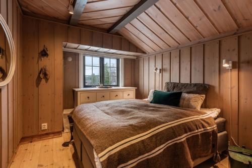 une chambre avec un lit dans une pièce aux murs en bois dans l'établissement Large cabin with spectacular views in Geilo, à Geilo