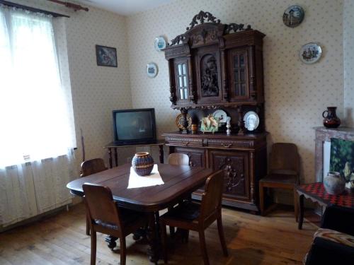 a dining room with a wooden table and a tv at Gîte de Peyrusse in Meauzac