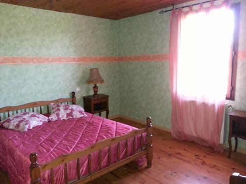 a bedroom with a bed with pink sheets and a window at Gîte de Viole in Monclar-de-Quercy