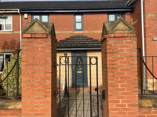 un cancello per una casa di mattoni con una porta nera di Fun by the Sea a Hartlepool