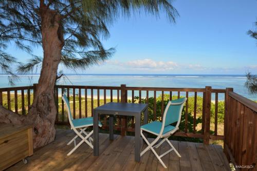una mesa y dos sillas en una terraza con vistas al océano en La Villa de la Plage en La Saline les Bains