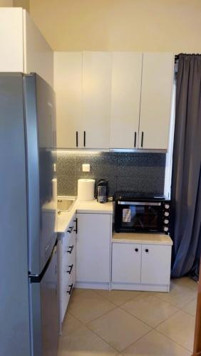 uma cozinha com armários brancos e uma geladeira preta em Kourouta's Diamond Apartment 1 em Kourouta
