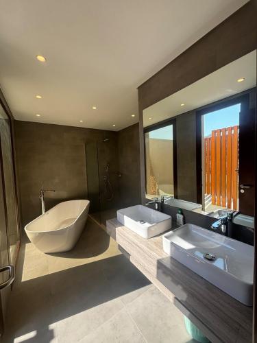 a bathroom with two sinks and a tub and a large mirror at Hawana Salalah Resort - FV 5 in Salalah