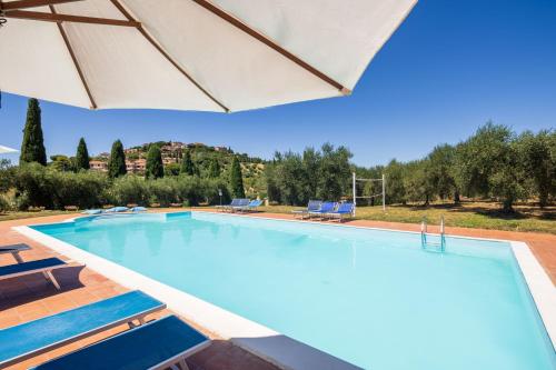 a large swimming pool with an umbrella at La Fontaccia 10 by VacaVilla in Montiano