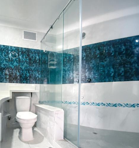 a bathroom with a toilet and a glass shower at Quiet studio apartment one block from the beach in Playa Bello Horizonte