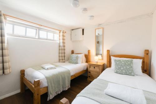 une chambre avec deux lits et une fenêtre dans l'établissement Shepherds Rest Cotswolds Cottage Farm Stay With Pool, à Lechlade