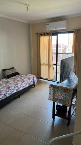 a bedroom with a bed and a chair and a window at Departamento Orlando, zona centro in Villa Carlos Paz