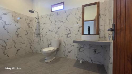 une salle de bain avec toilettes et miroir dans l'établissement Village Corner Homestay, à Kuta Lombok