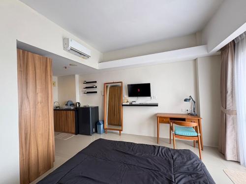 a bedroom with a bed and a desk and a television at Cozy Bogor Icon Studio Apt bogor W Pool in Kedunghalang