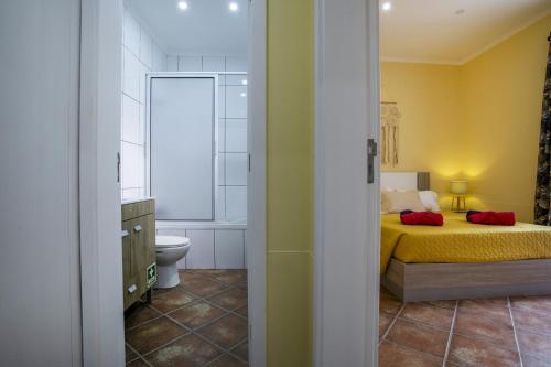 a bedroom with a bed and a bathroom with a toilet at Furnas Cozy Inn in Furnas
