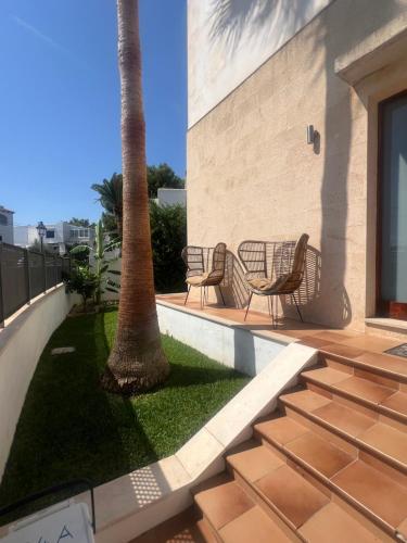 eine Terrasse mit 2 Stühlen und einer Palme in der Unterkunft Villa Ferrera Select A in Cala Ferrera