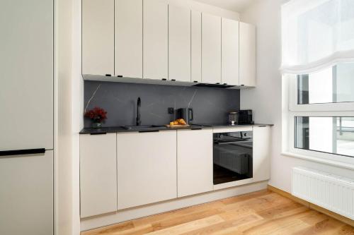 a kitchen with white cabinets and a window at Luxury Apartment with Parking & Terrace Remote Work by Renters Prestige in Poznań