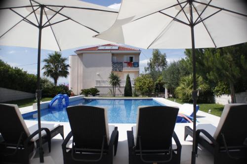 una piscina con sedie e ombrelloni davanti a una casa di Geräumige Ferienwohnung Mit Privatem Sonnenbalkon a Splitska