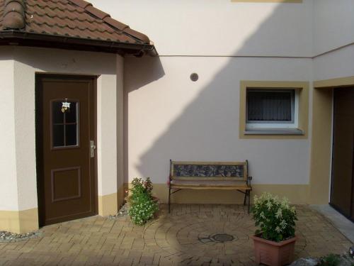 un banc assis à côté d'un bâtiment avec une porte dans l'établissement Ferienwohnung Mit Blick Zur Wallfahrtskirche, à Ebensfeld
