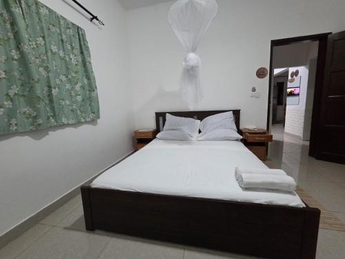 a bedroom with a bed with white sheets and a window at Passadeira Garden in São Tomé