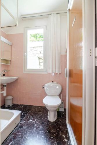a bathroom with a toilet and a sink and a window at Villa Caslano in Caslano